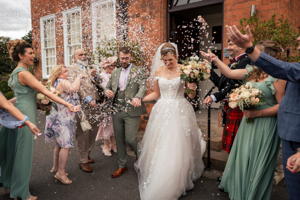 Bride and groom walking through a confetti tunnel for a personalised fun wedding