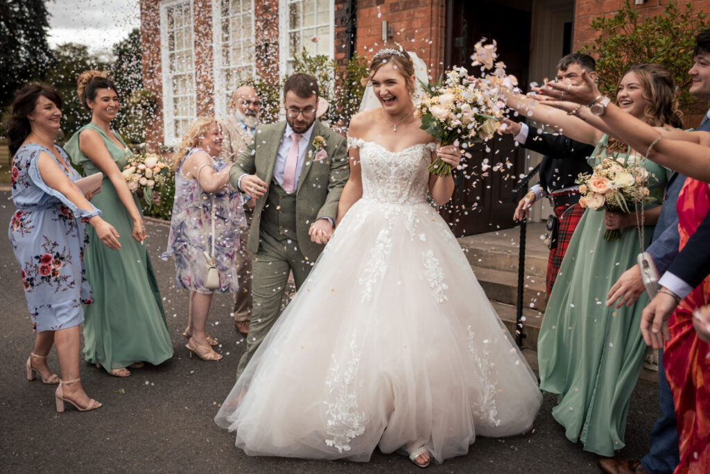 Bride and groom walking through a confetti tunnel for a personalised fun wedding