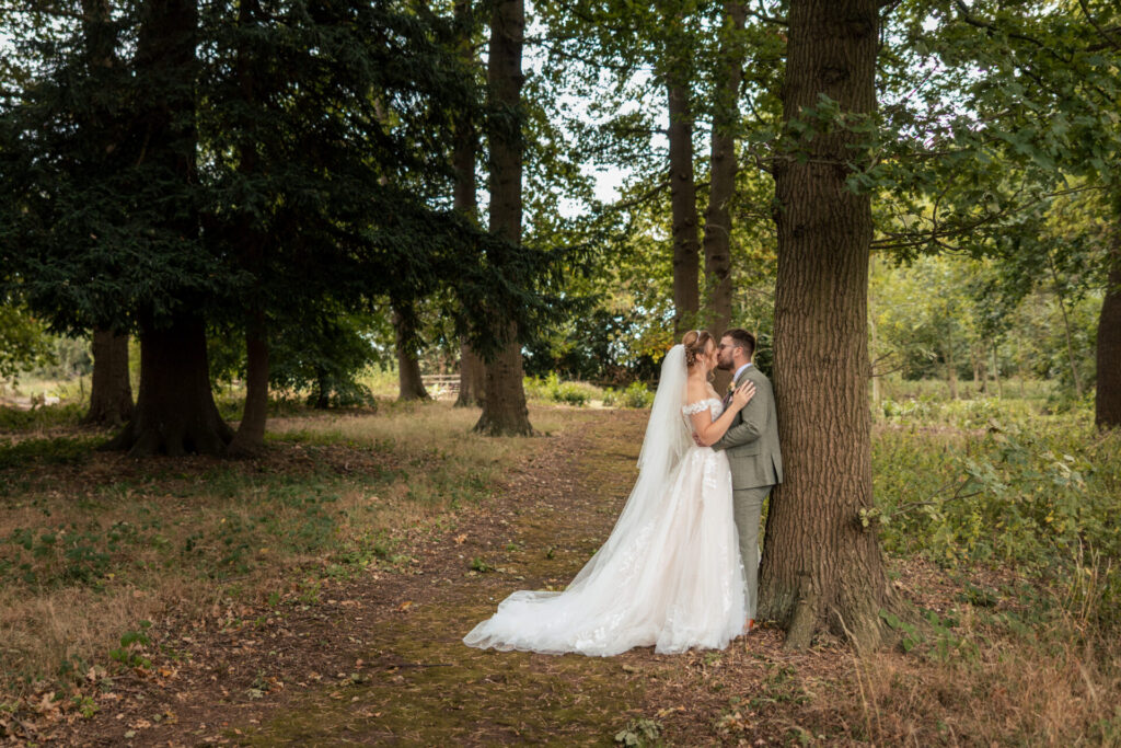 Bride and groom leaning against a tree in the woodlands for a personalised fun wedding